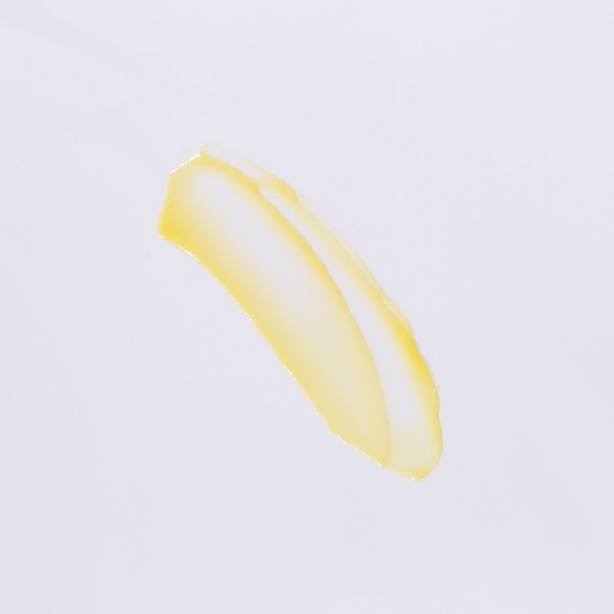 A smear of pale yellow cream or balm on a plain white background.